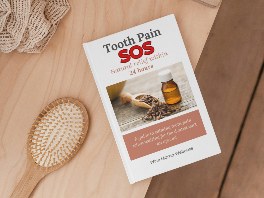 Flat lay of the Tooth Pain SOS Guide beside natural remedies like clove oil and sea salt on a wooden surface.