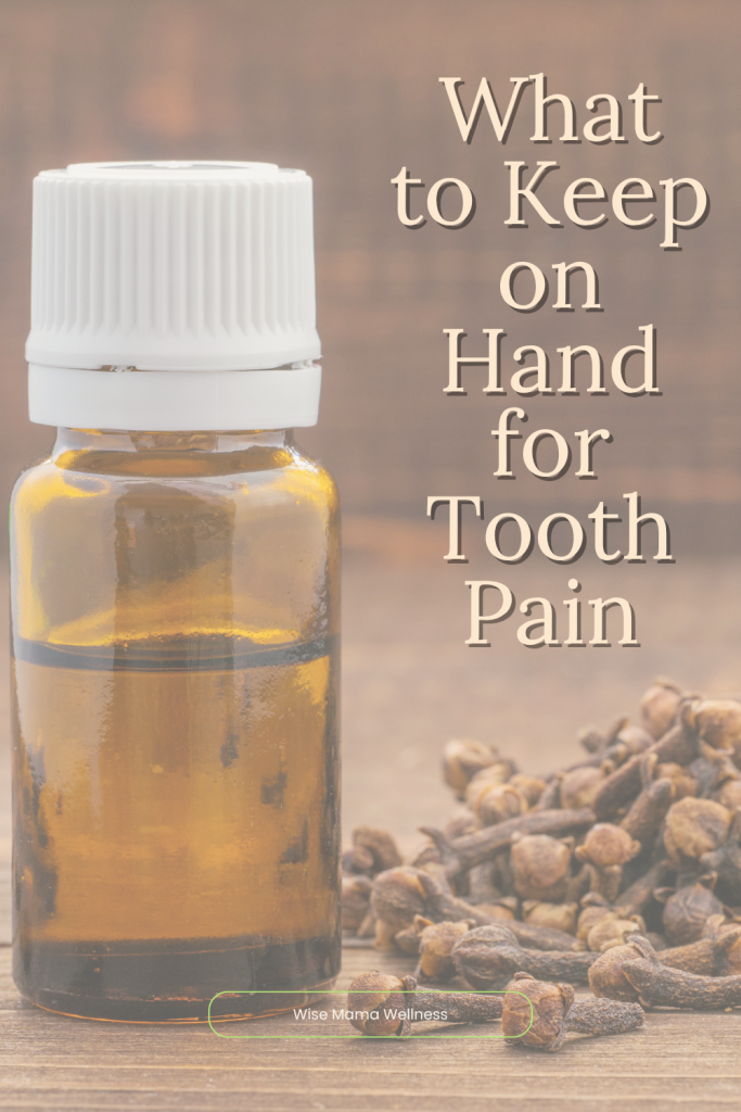 Bottle of clove oil surrounded by whole cloves on a wooden surface for natural tooth pain relief.